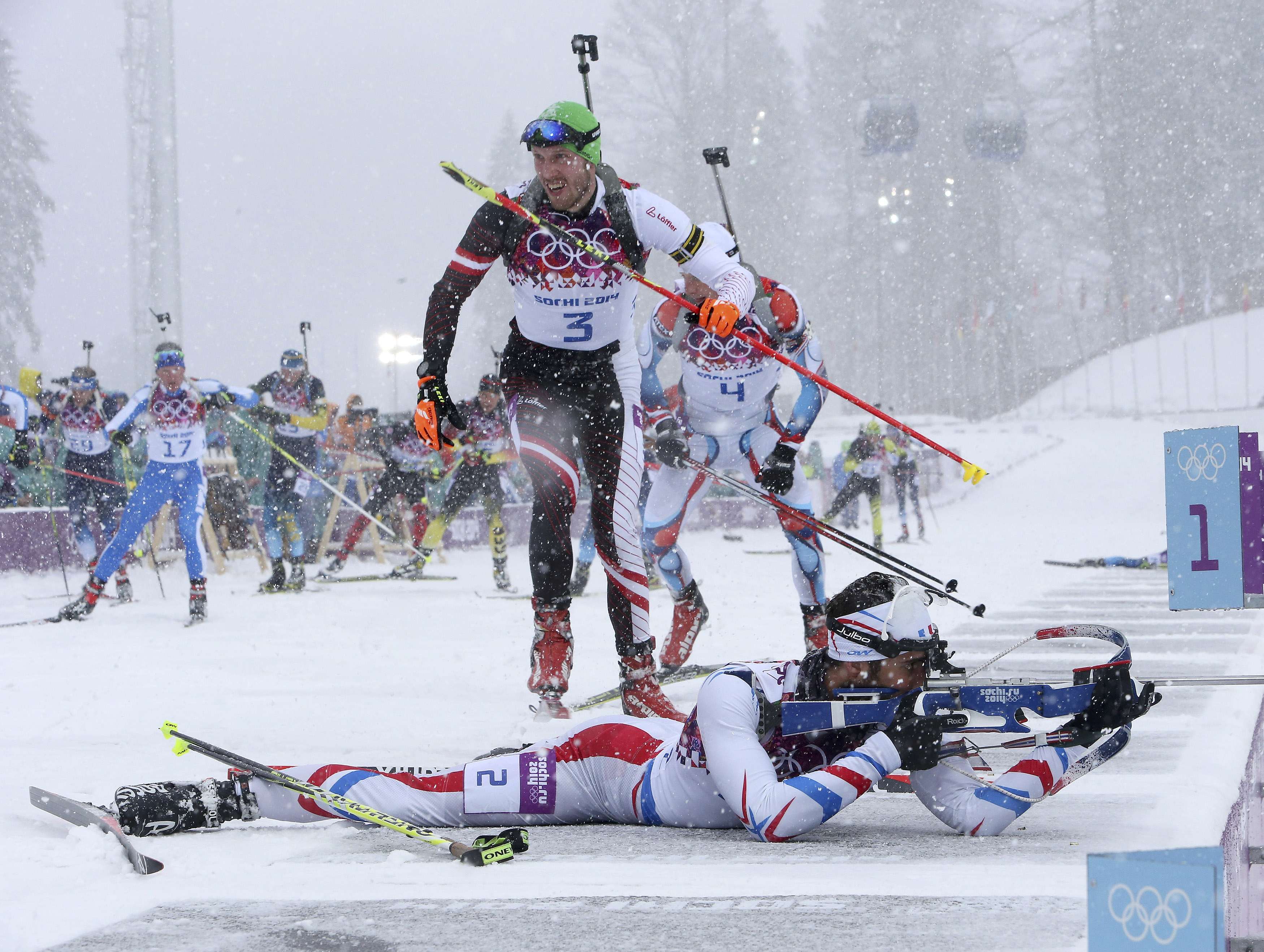 France's Martin Fourcade (bottom) shoots as Austria's Dominik Landertinger (C) leaves the shooting range during the men's biathlon 15km mass start event at the Sochi 2014 Winter Olympics in Rosa Khutor February 18, 2014. REUTERS/Sergei Karpukhin (RUSSIA - Tags: SPORT BIATHLON OLYMPICS TPX IMAGES OF THE DAY) ATTENTION EDITORS: PICTURE 04 OF 20 FOR PACKAGE 'SOCHI - EDITOR'S CHOICE' TO FIND ALL SEARCH 'EDITOR'S CHOICE - 18 FEBRUARY 2014' ORG XMIT: PXP04