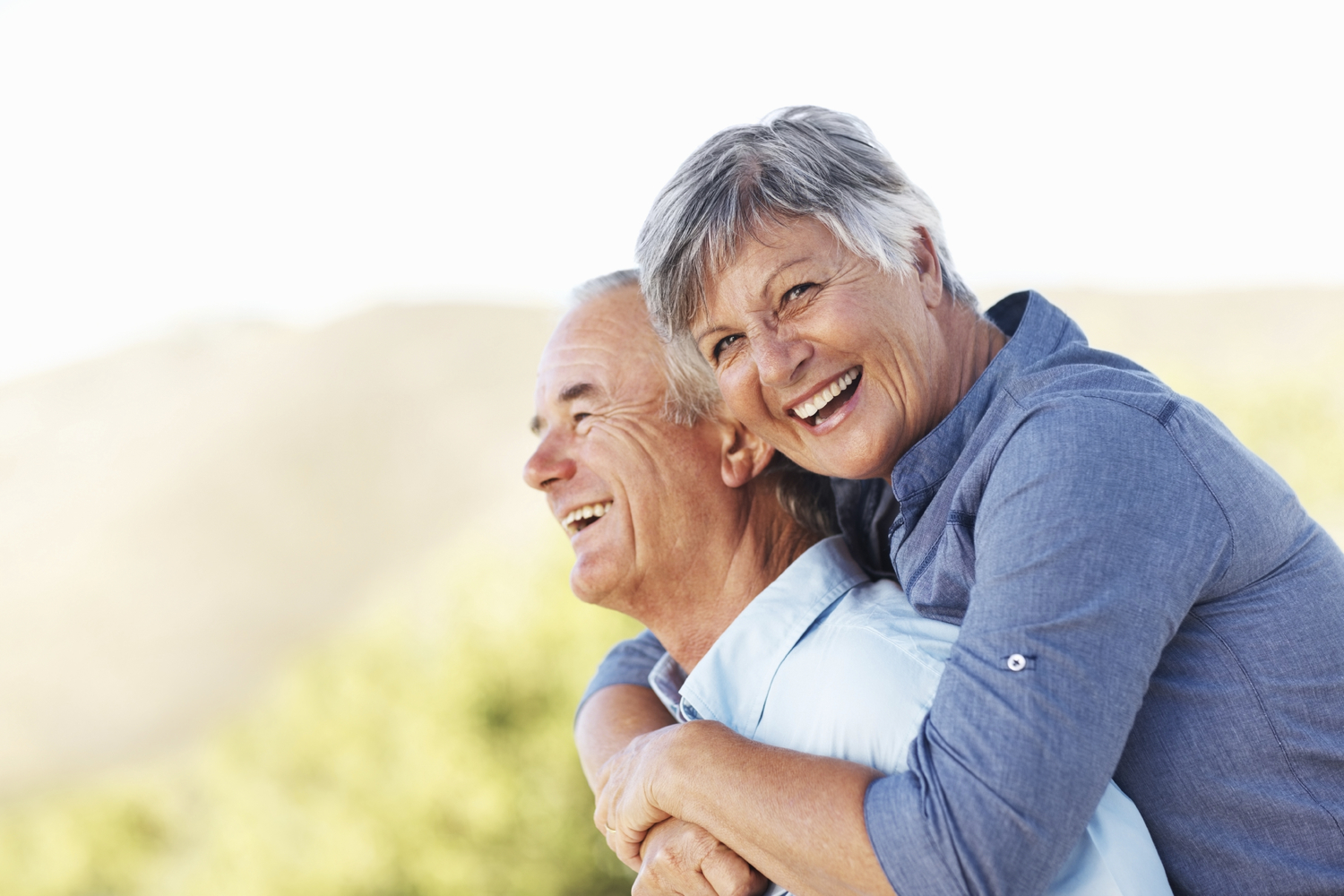 Portrait of cheerful mature woman smiling while embracing man outdoors